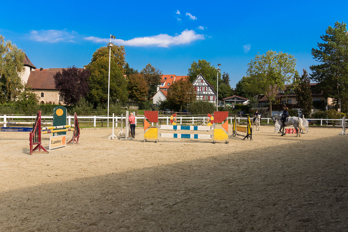 Sand-Außenplatz mit Springhindernissen, Blick aufs Dorf