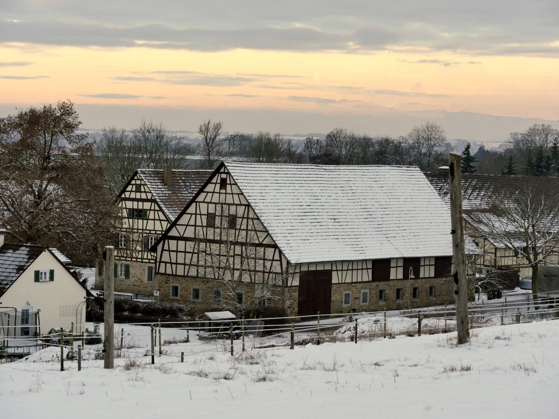 Schneebedeckte Koppel und Fachwerkgebäude des Hofguts im Winter